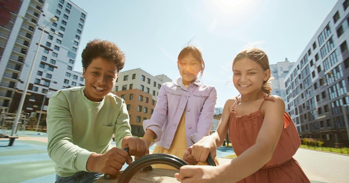 A group of diverse children playing outdoors on a sunny day, illustrating peer interaction and social confidence.